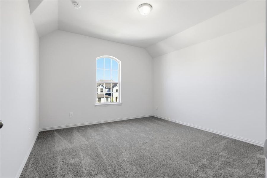 Spare room featuring lofted ceiling and light carpet