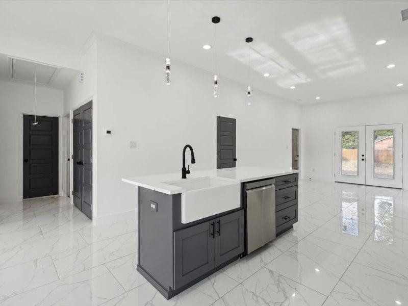 Kitchen with light tile patterned floors, french doors, sink, a kitchen island with sink, and stainless steel dishwasher