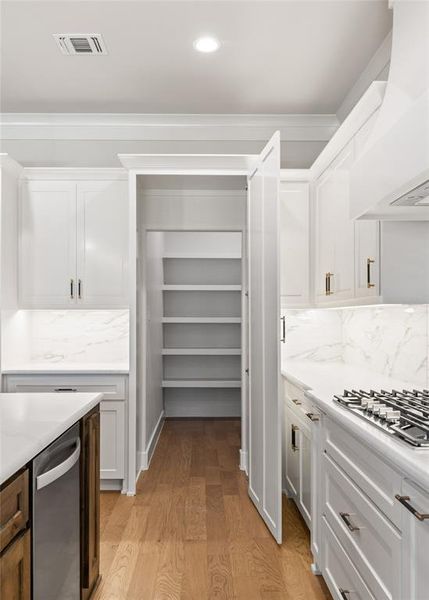 Kitchen with light wood-style floors, stainless steel appliances, decorative backsplash, dual tone cabinets, and recessed lighting