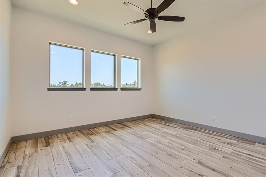 Empty room with light hardwood / wood-style flooring and ceiling fan