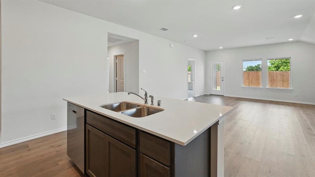 Kitchen featuring dark brown cabinetry, recessed lighting, open floor plan, light wood-type flooring, and stainless steel dishwasher