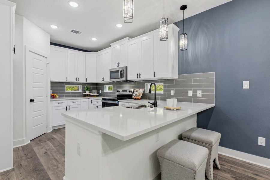 A well-appointed kitchen showcases sleek white cabinetry, luminous quartz countertops, and modern pendant lighting.