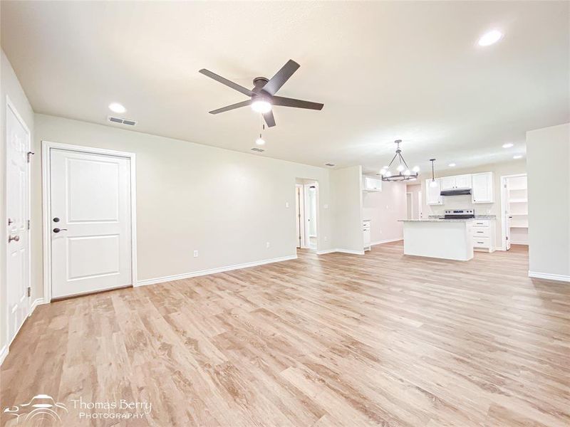 Unfurnished living room with recessed lighting, a chandelier, light wood finished floors, and a ceiling fan Unfurnished living room with recessed lighting, a chandelier, light wood finished floors, and a ceiling fan