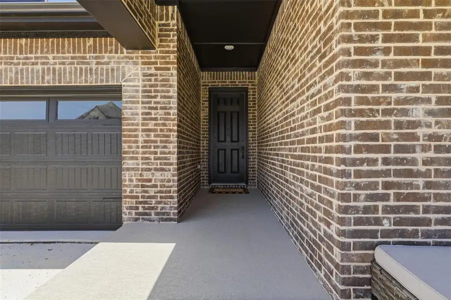Brick facade with dark garage door, recessed entryway, and a solid black front door Brick facade with dark garage door, recessed entryway, and a solid black front door