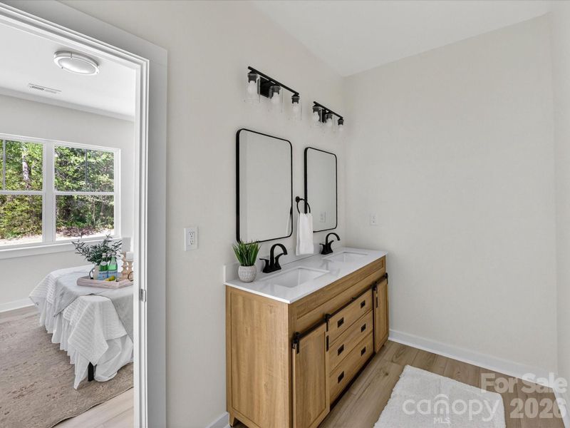 Modern primary bath vanity featuring dual sinks, sleek fixtures, and a stylish wood cabinet with ample storage. Modern primary bath vanity featuring dual sinks, sleek fixtures, and a stylish wood cabinet with ample storage.