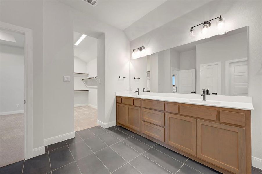 Bathroom featuring double vanity, a spacious closet, dark tile patterned flooring, and dark carpet