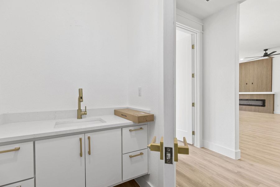 Bathroom featuring vanity, a ceiling fan, light wood-style floors, and a large fireplace