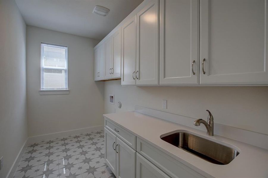 Laundry room has charming floor tile, a sink and LOTS of cabinets