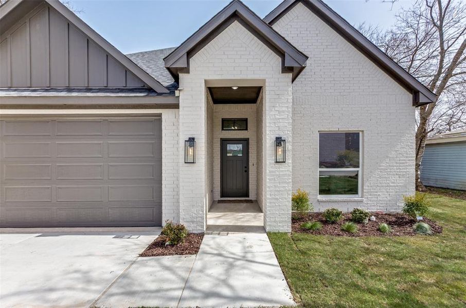 View of front of home featuring an attached garage, board and batten siding, and brick siding