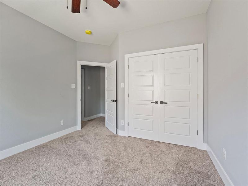 Unfurnished bedroom featuring carpet floors, a closet, baseboards, and ceiling fan