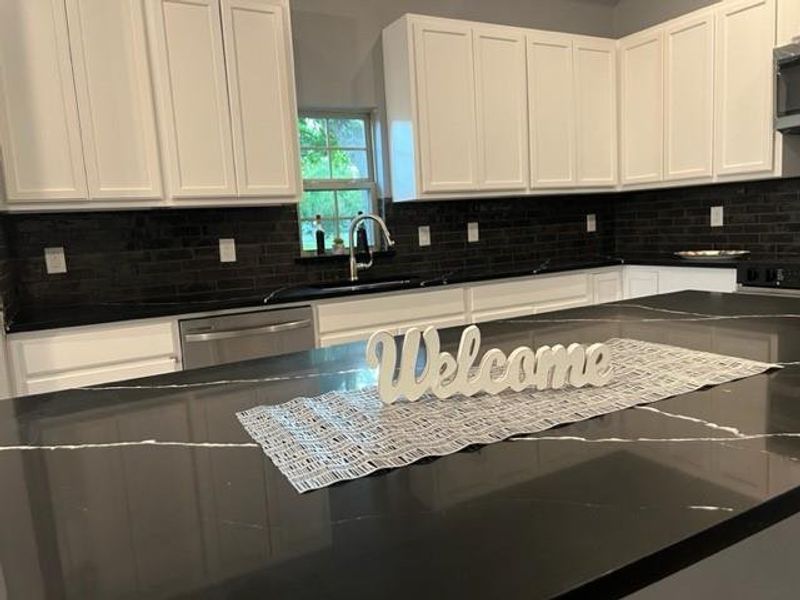 Kitchen with sink, appliances with stainless steel finishes, tasteful backsplash, and white cabinetry