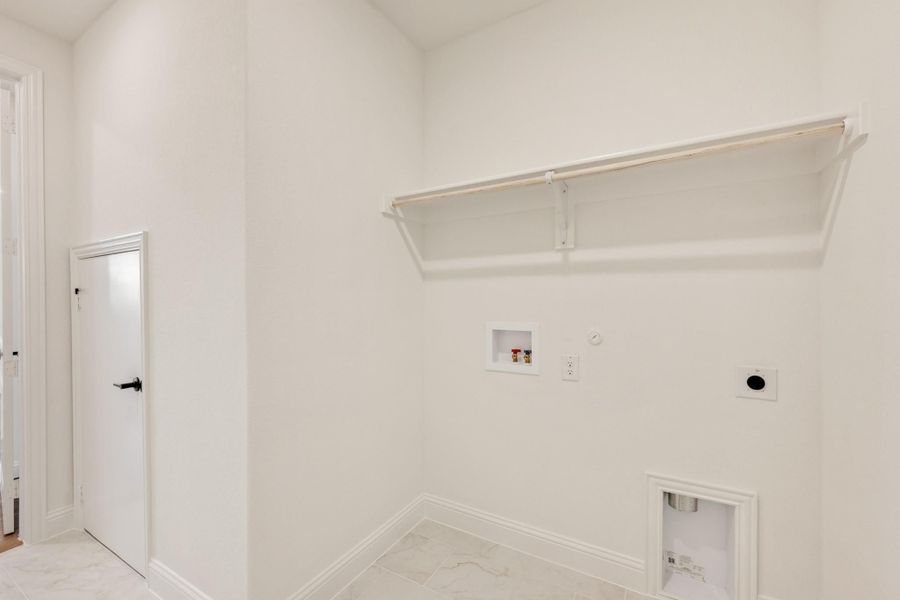 Laundry room with white walls, wall-mounted shelf, washer hookups, and dryer vent connection