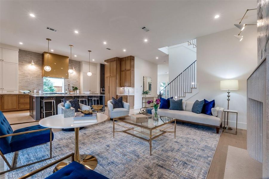 Living area with recessed lighting, light wood finished floors, stairs, and visible vents Living area with recessed lighting, light wood finished floors, stairs, and visible vents