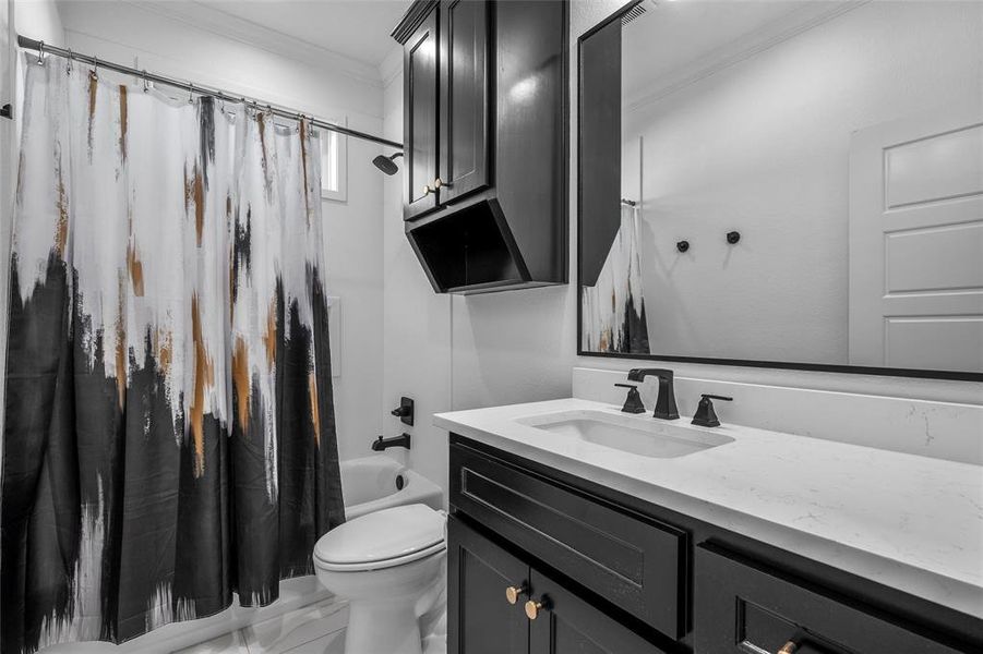 Bathroom featuring shower / tub combo, vanity, crown molding, and marble finish flooring Bathroom featuring shower / tub combo, vanity, crown molding, and marble finish flooring