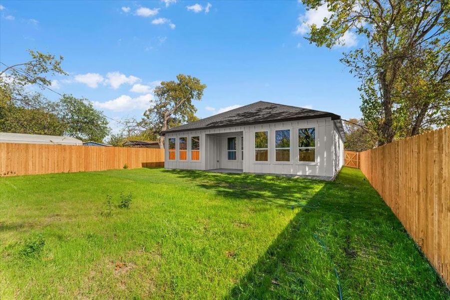 Rear view of house with a patio area, a fenced backyard, and a shingled roof