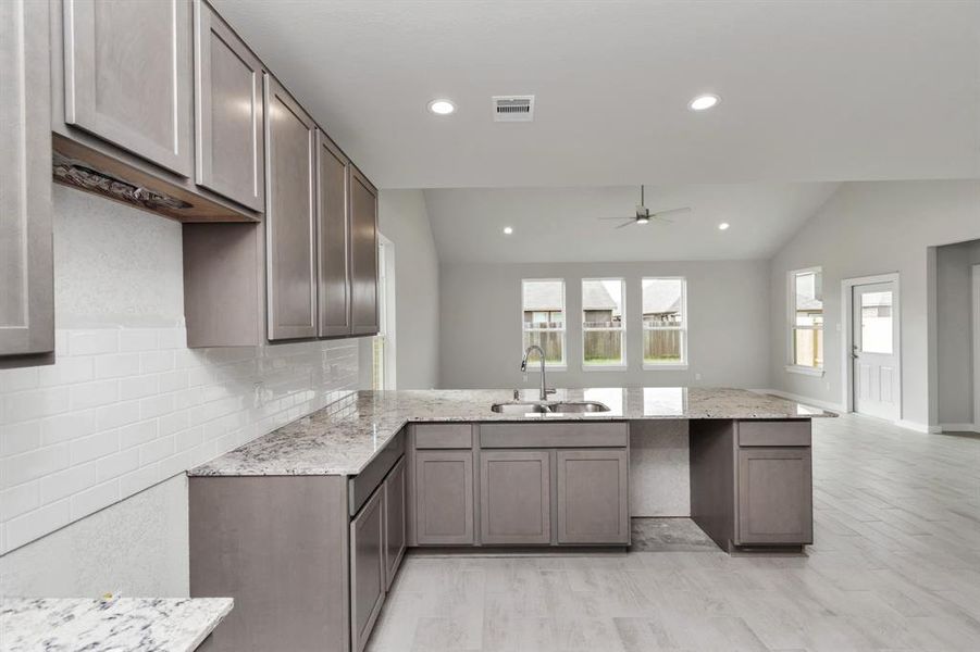 Culinary haven, featuring granite countertops, a tile backsplash, stainless steel appliances, 42” upper cabinets, and undercabinet lighting. Sample photo of completed home with similar floor plan. As-built interior colors and selections may vary.