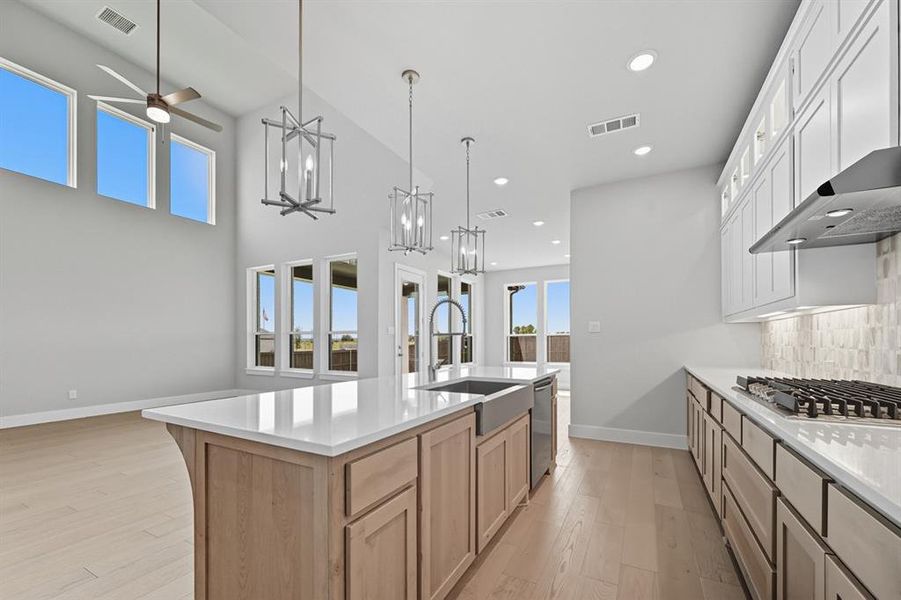 Kitchen featuring healthy amount of natural light, decorative light fixtures, white cabinets, and recessed lighting