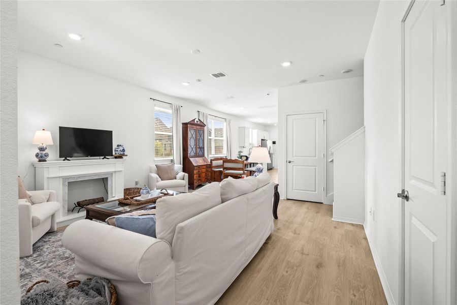 Recessed lighting illuminates this bright living space with inviting fireplace and wood flooring.