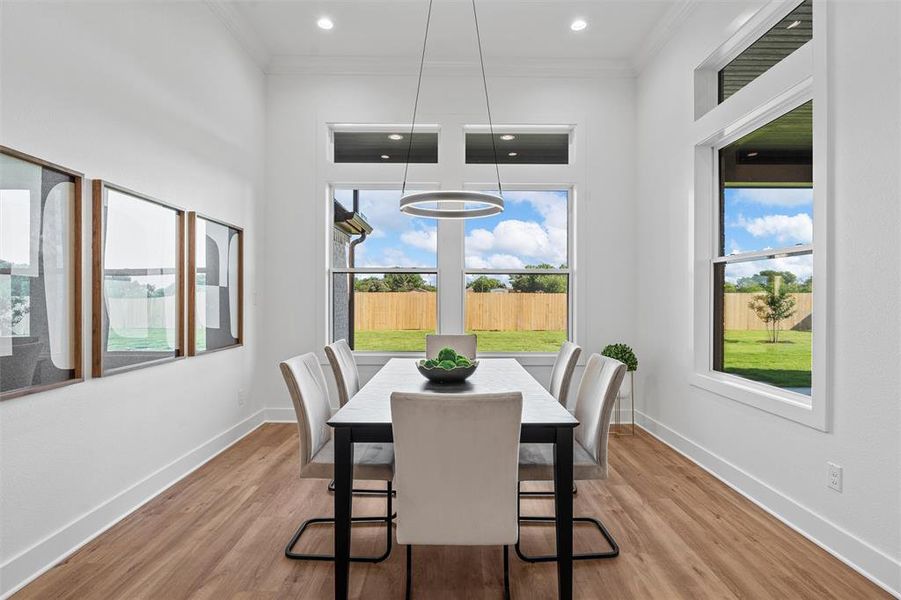 Dining room featuring plenty of natural light, crown molding, light wood-style flooring, and recessed lighting
