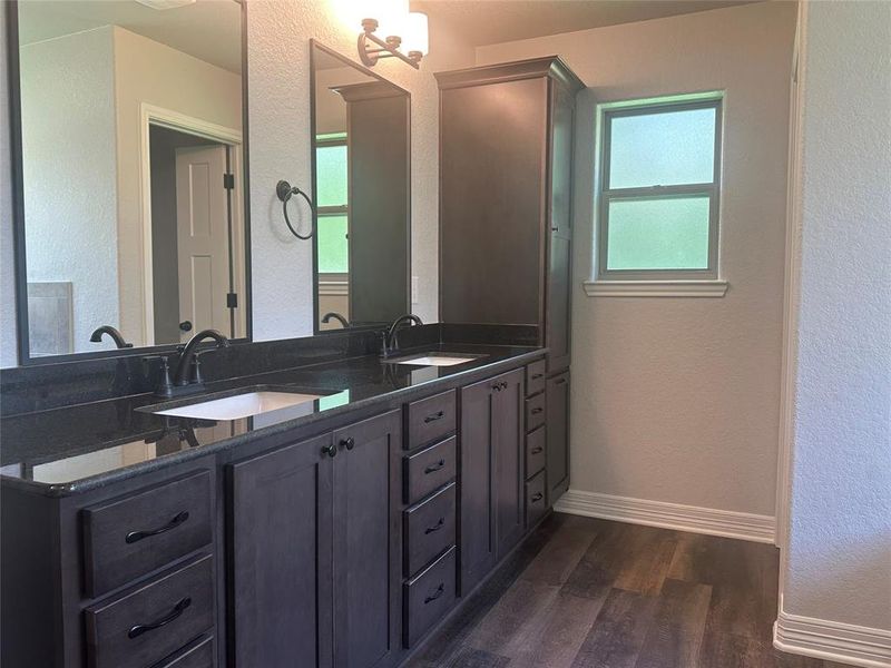 Full bath featuring wood finished floors, double vanity, healthy amount of natural light, and a textured wall