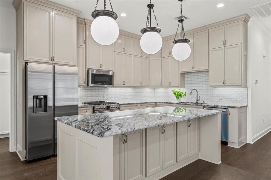 Kitchen with appliances with stainless steel finishes, dark wood-style flooring, light stone countertops, backsplash, and recessed lighting Kitchen with appliances with stainless steel finishes, dark wood-style flooring, light stone countertops, backsplash, and recessed lighting