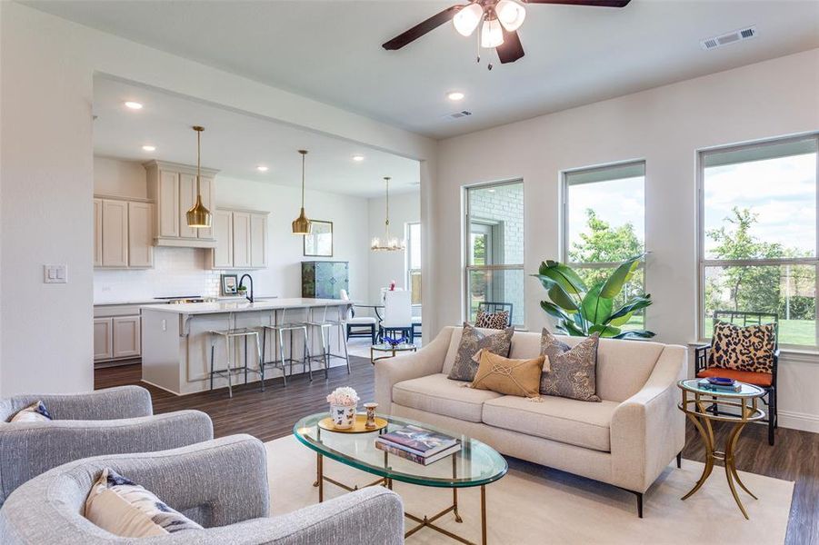 Living room featuring ceiling fan with notable chandelier, hardwood / wood-style flooring, and sink