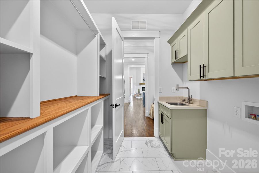 Custom cabinetry, open shelving, and a utility sink give this laundry room the same thoughtful design carried throughout the rest of the home