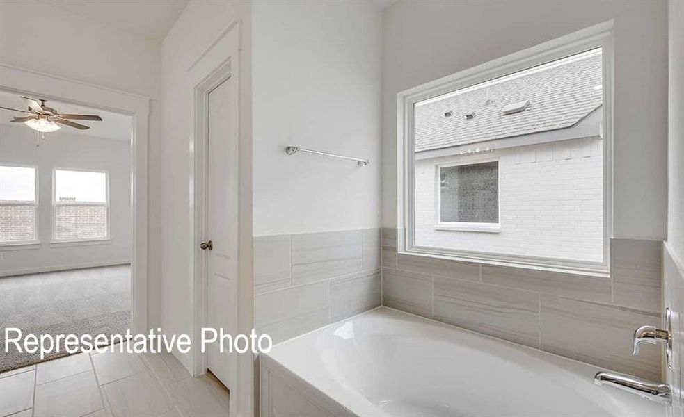 Bathroom with a bathing tub, ceiling fan, and tile patterned floors