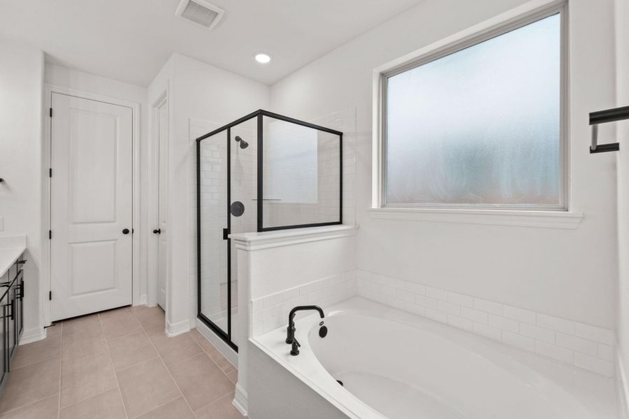 This additional view of your primary bathroom features tile flooring, fresh paint, walk-in shower, a separate garden tub, and a large walk-in closet.
