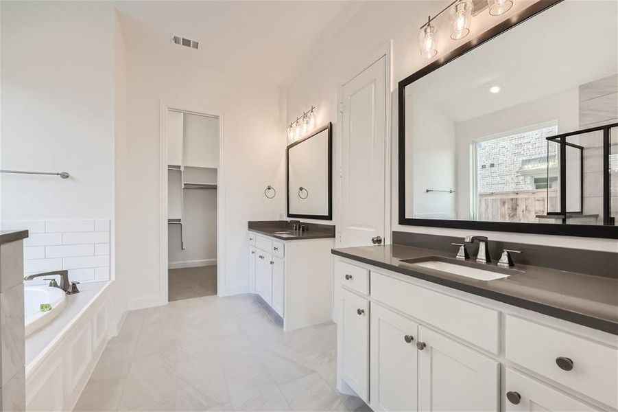 Bathroom featuring tile flooring, a relaxing tiled bath, and double sink vanity