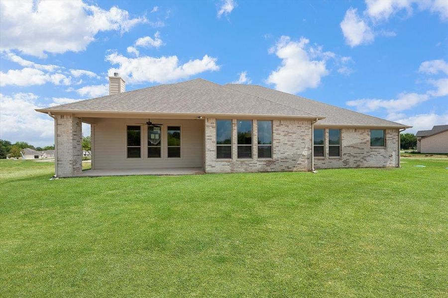 Rear view of property featuring a yard and a patio