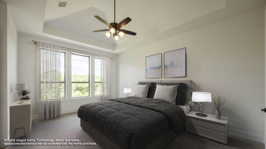 Carpeted bedroom featuring a raised ceiling and ceiling fan