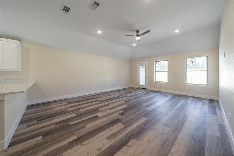 Unfurnished living room featuring recessed lighting, visible vents, vaulted ceiling, and baseboards