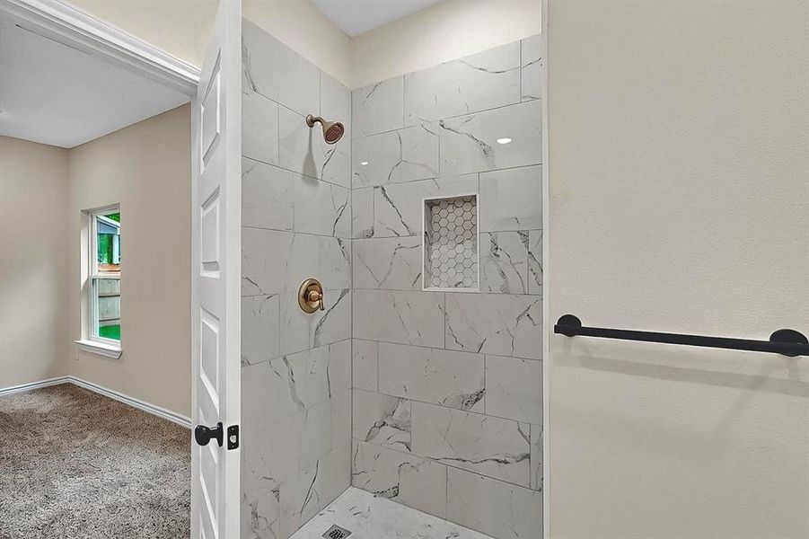 Full bathroom featuring baseboards and a tile shower Full bathroom featuring baseboards and a tile shower