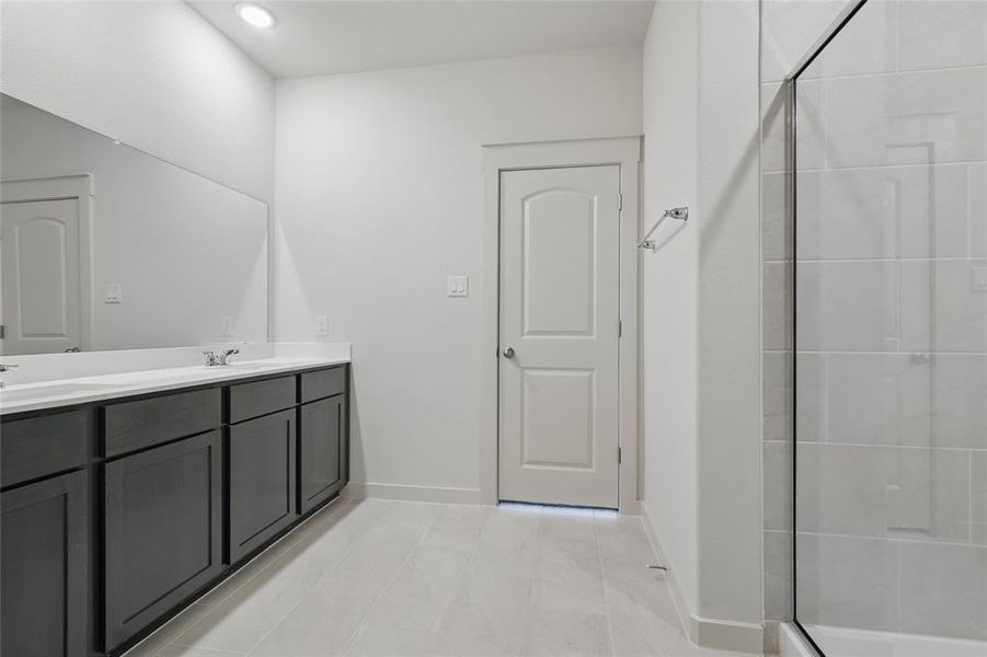 Full bath with double vanity, a stall shower, light tile patterned floors, and recessed lighting