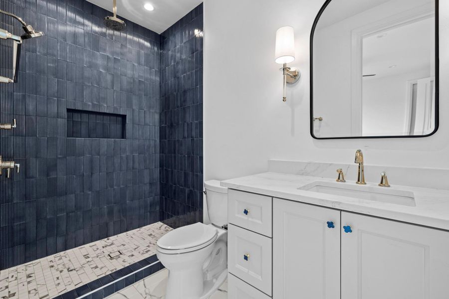 Full bath with a tile shower, toilet, vanity, and marble finish flooring