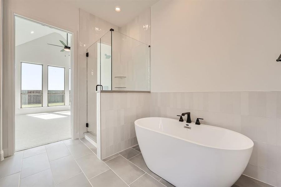 Main bathroom with tile walls, tile patterned flooring, separate shower and tub, and vaulted ceiling