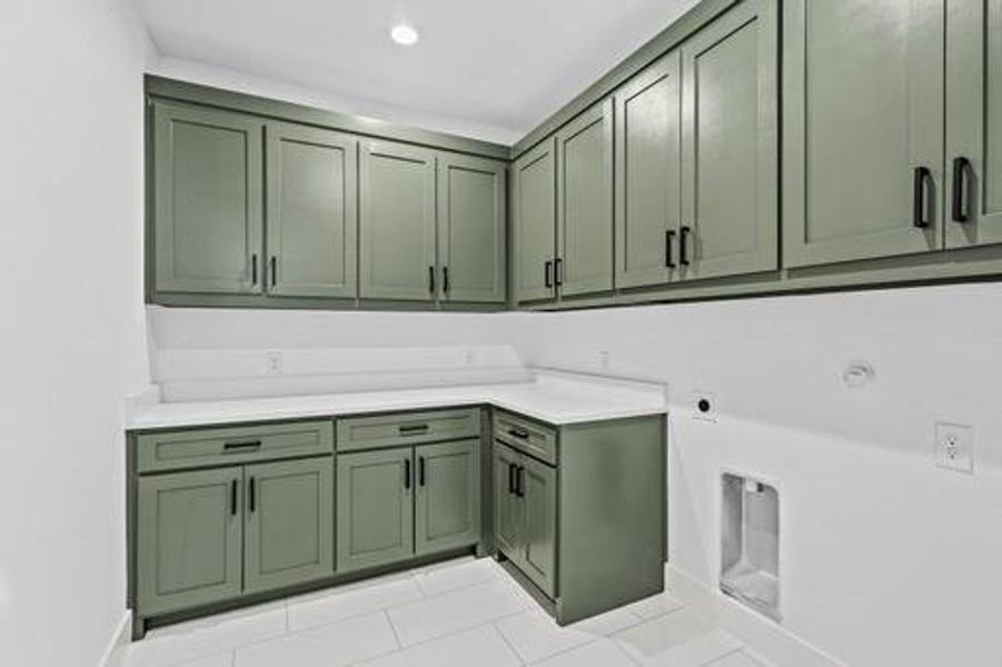 Clothes washing area with cabinets, light tile patterned floors, hookup for a gas dryer, and hookup for an electric dryer