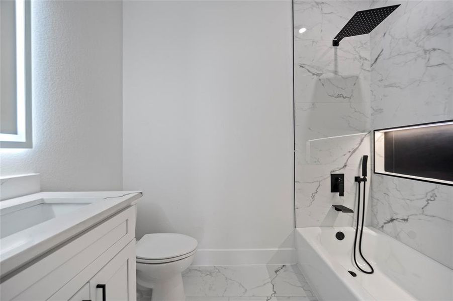 Full bathroom featuring tiled shower / bath combo, vanity, and toilet