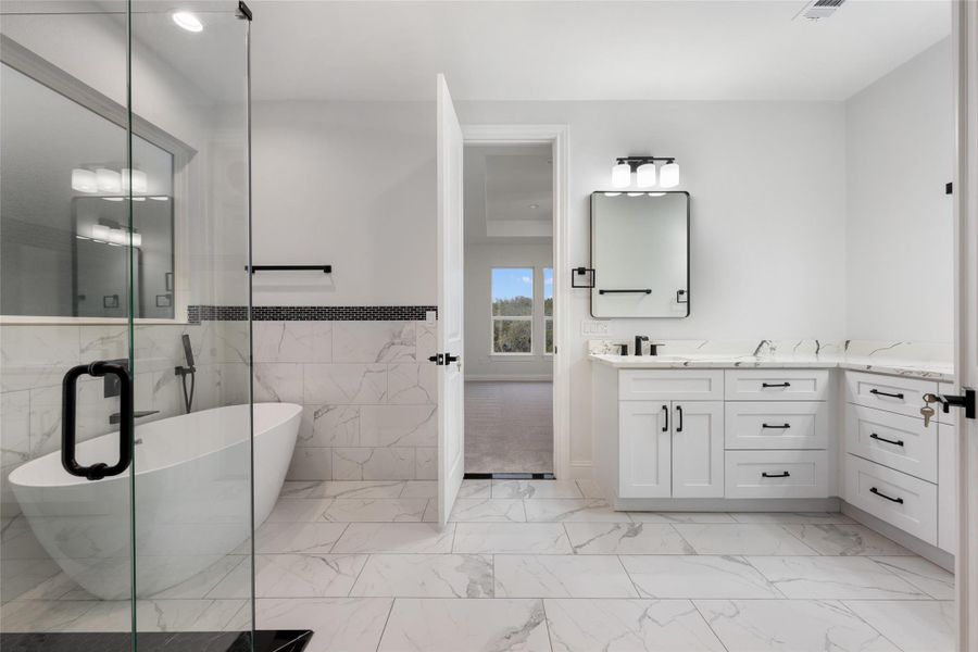 Bathroom featuring vanity, a soaking tub, tile walls, a shower stall, and light marble finish floors