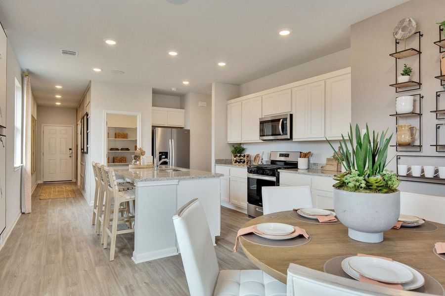 A contemporary kitchen features an inviting dining area, sleek white cabinetry, and a granite-topped island with seating. A contemporary kitchen features an inviting dining area, sleek white cabinetry, and a granite-topped island with seating.