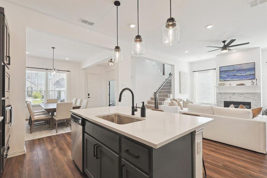 Kitchen with sink, dark hardwood / wood-style flooring, hanging light fixtures, and a kitchen island with sink