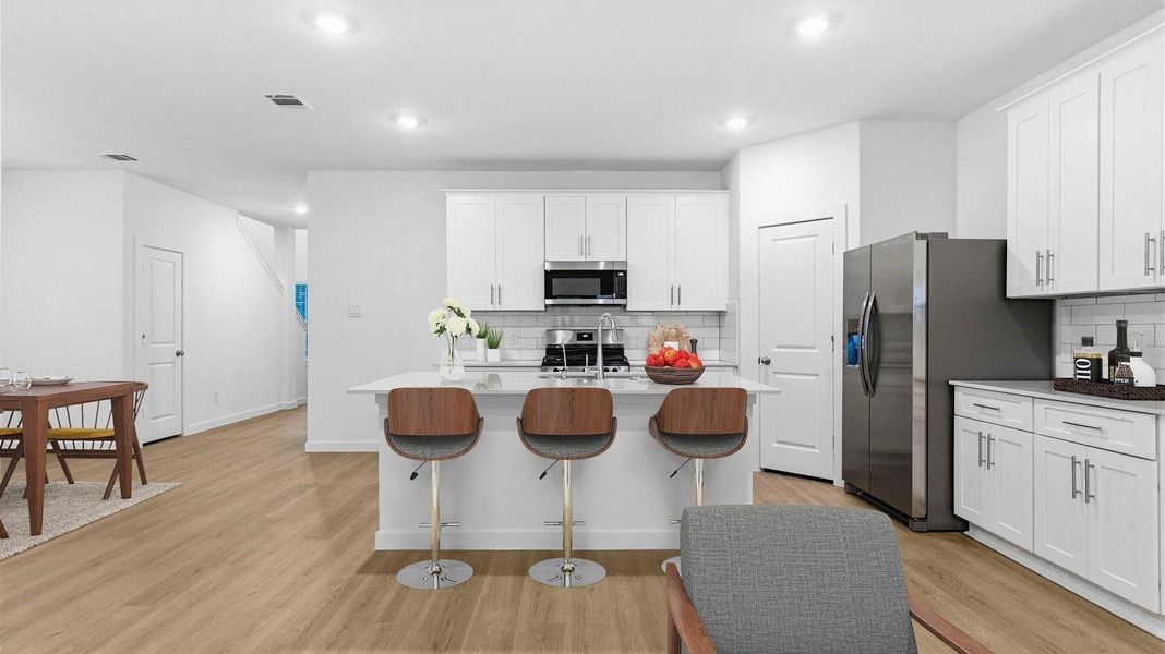 An open concept kitchen with an island with bar seating and access to the living and dining areas. An open concept kitchen with an island with bar seating and access to the living and dining areas.