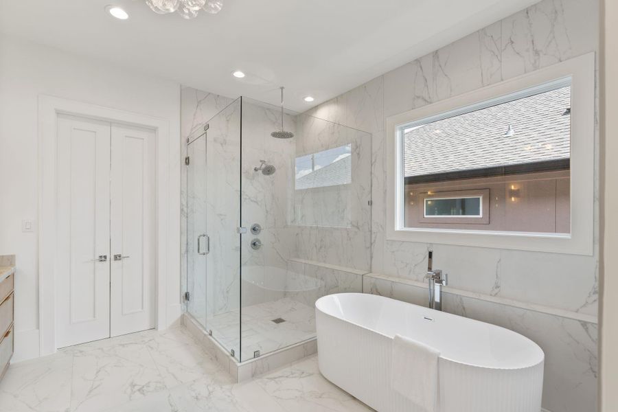 A glass-enclosed walk-in shower with full-height marble tile sits alongside a freestanding soaking tub, offering a true retreat-like experience.