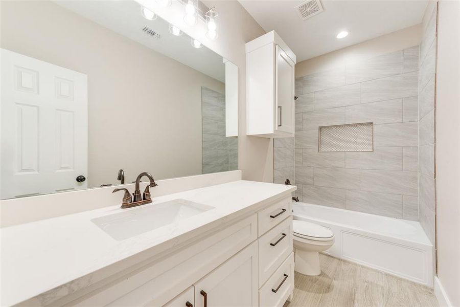 Full bathroom featuring vanity, tiled shower / bath, and toilet