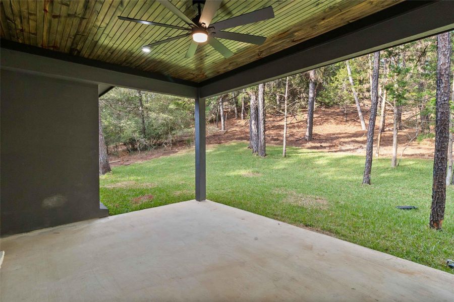 View of green lawn featuring a patio and ceiling fan