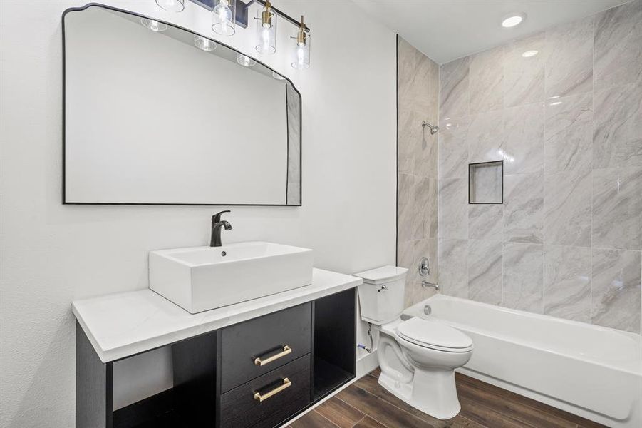 Full bathroom with toilet, vanity, hardwood / wood-style floors, and tiled shower / bath combo