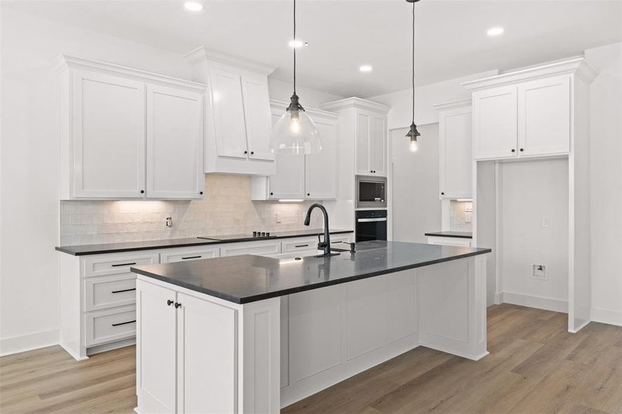 Kitchen featuring decorative backsplash, white cabinets, and light wood-style flooring