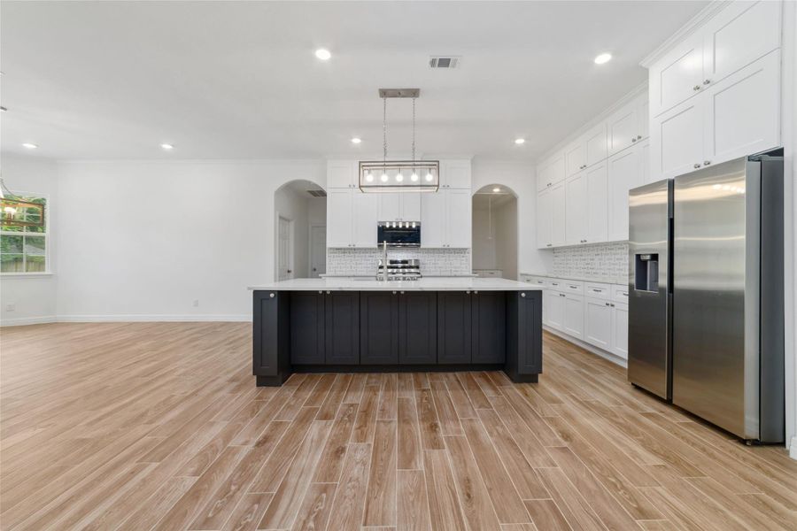 View from living room into the kitchen. Wood-look tile floors continue throughout the house. Large center island with breakfast bar. View from living room into the kitchen. Wood-look tile floors continue throughout the house. Large center island with breakfast bar.