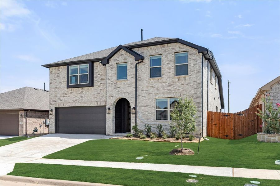 Two-story brick home with arched entry, two-car garage, and manicured front lawn